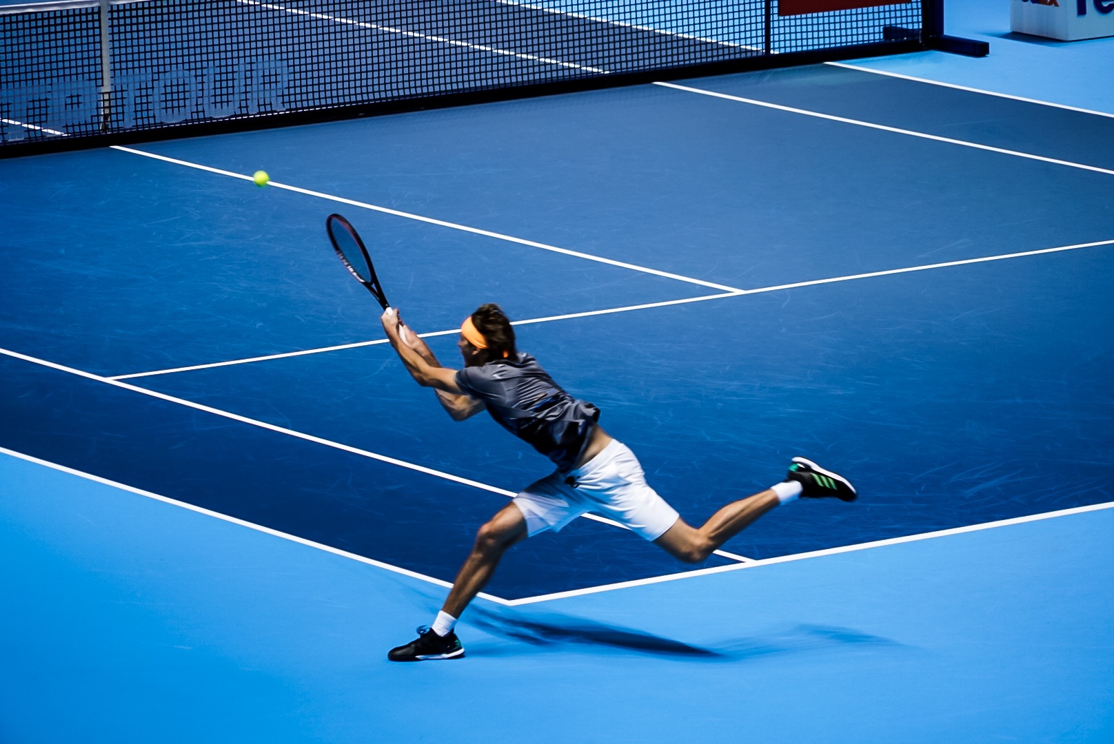 Alexander Zverev stretching for a backhand on an indoor court