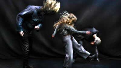 100%WET (Jakob Birch, Casper Munns and Sanna Heinstedt) headbanging against a black backdrop