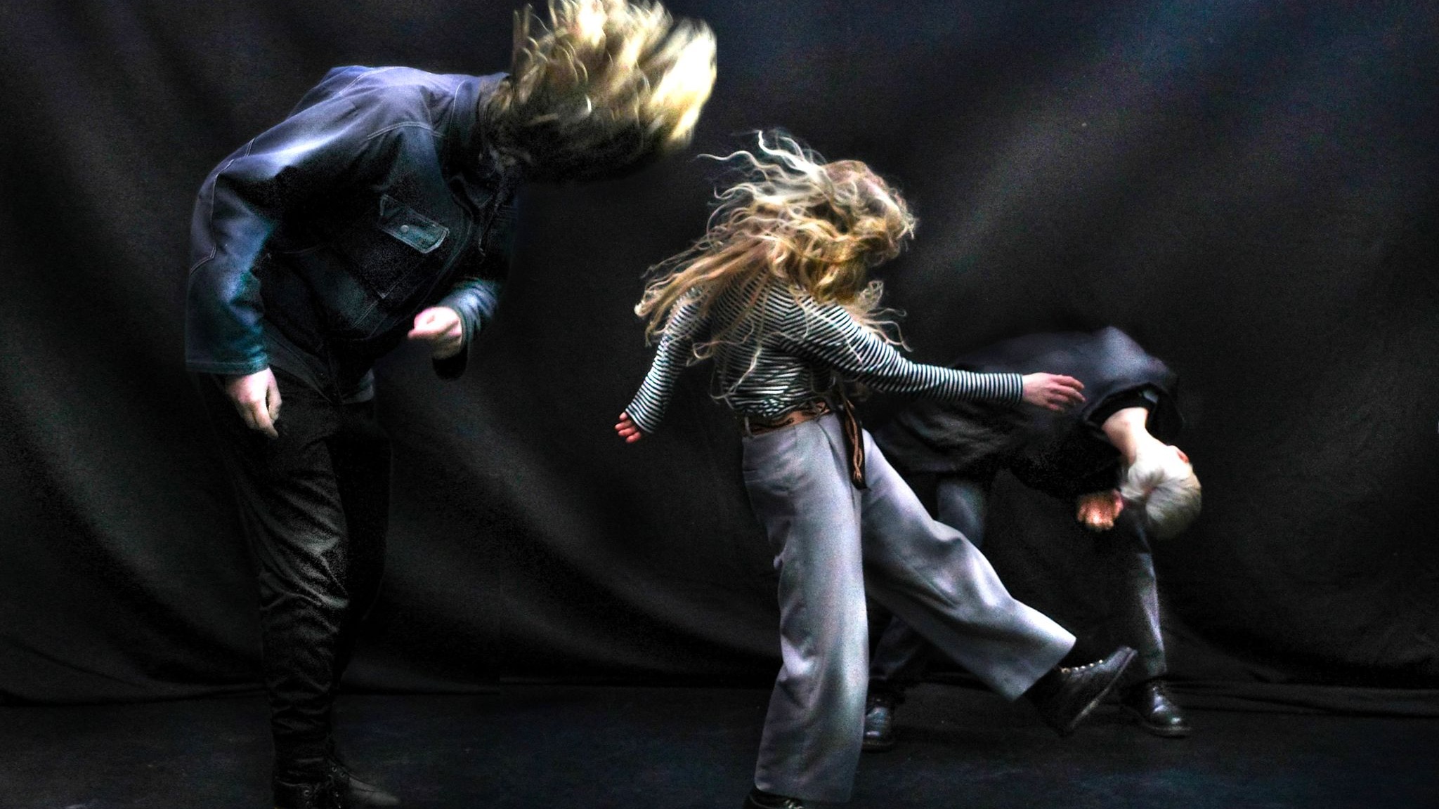 100%WET (Jakob Birch, Casper Munns and Sanna Heinstedt) headbanging against a black backdrop