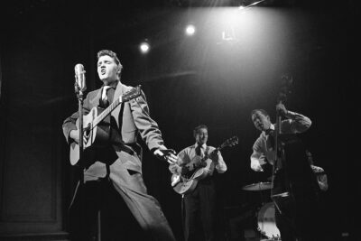 Elvis Presley singing on stage with Scotty Moore and Bill Black