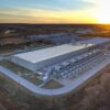 Aerial view of Google's data center in Council Bluffs, Iowa, at sunset, with rows of cooling units along a long low building