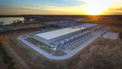 Aerial view of Google's data center in Council Bluffs, Iowa, at sunset, with rows of cooling units along a long low building