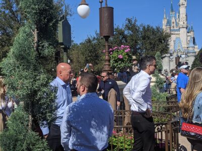 Bob Chapek, left, in a light blue shirt and Josh D’Amaro, right, in a white shirt, at Magic Kingdom with Cinderella Castle behind them