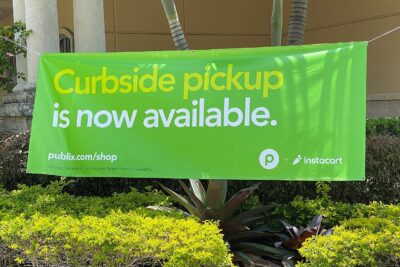 A green Instacart and Publix banner announcing curbside grocery pickup outside a Publix supermarket in West Miami
