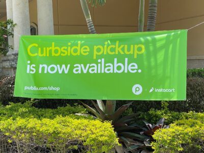 A green Instacart and Publix banner announcing curbside grocery pickup outside a Publix supermarket in West Miami