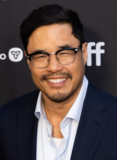 Randall Park smiling in black-rimmed glasses and a navy blazer at the Girl Group premiere at TIFF in September 2026