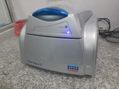 A Qiagen Rotor-Gene Q real-time PCR cycler with its lid closed and status light on, on a laboratory bench