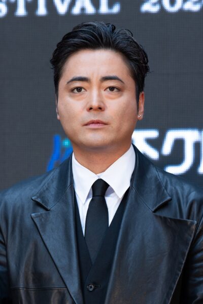 Takayuki Yamada, with swept-back dark hair, in a black leather coat, white shirt and black tie on the red carpet of the Tokyo International Film Festival, October 2024