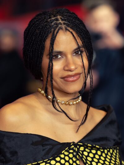 Zazie Beetz smiling on the red carpet of the Berlin International Film Festival in 2026, wearing fine braids and a pearl necklace