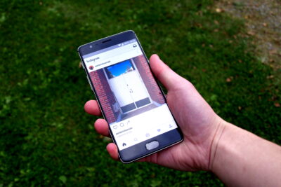 The Instagram app open on a smartphone held in one hand above a lawn