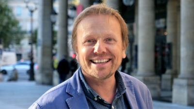 Laurent Stocker smiling in a blue jacket under the colonnade outside the Comédie-Française in Paris, October 2021