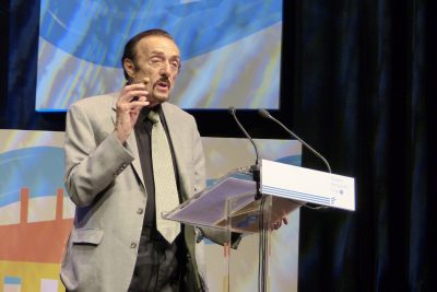 Philip Zimbardo speaking at a lectern in a grey jacket, Budapest, May 2017