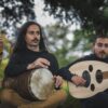 Al Tayr Ensemble musicians playing a recorder, a goblet drum and an oud outdoors