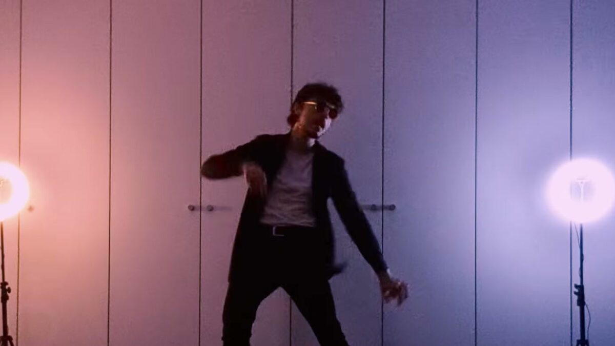 Albert Feiler dancing between two ring lights in a pink and violet lit room