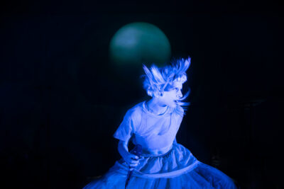 Norwegian singer AURORA performing on stage under blue light