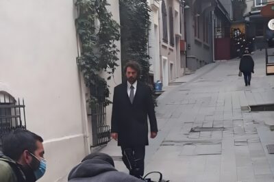 Birkan Sokullu in a dark suit walking down a Beyoğlu street while filming Masumlar Apartmanı, Istanbul, 2020
