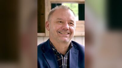 Bob Mortimer smiling in a navy jacket and checked shirt during a 2017 interview for the short film Lunch