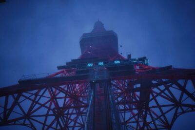Looking up at the red steel lattice of Tokyo Tower at night in BrokenLore ASCEND