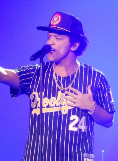 Bruno Mars singing into a microphone on stage during the 24K Magic World Tour in 2017