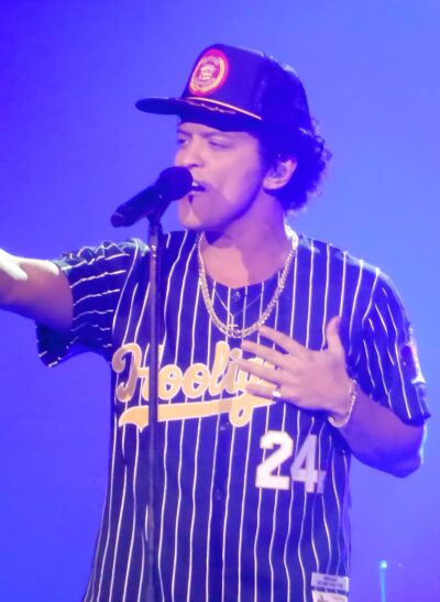 Bruno Mars singing into a microphone on stage during the 24K Magic World Tour in 2017