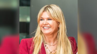 Corinna Schumacher smiling in a red jacket at the North Rhine-Westphalia State Prize ceremony in Cologne, July 2022