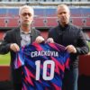 Actors Xavi Espinosa and Ivan Labanda, in character as José Mourinho and Hansi Flick, hold a Crackòvia number 10 shirt at the Spotify Camp Nou