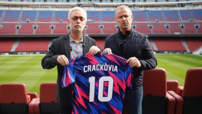 Actors Xavi Espinosa and Ivan Labanda, in character as José Mourinho and Hansi Flick, hold a Crackòvia number 10 shirt at the Spotify Camp Nou