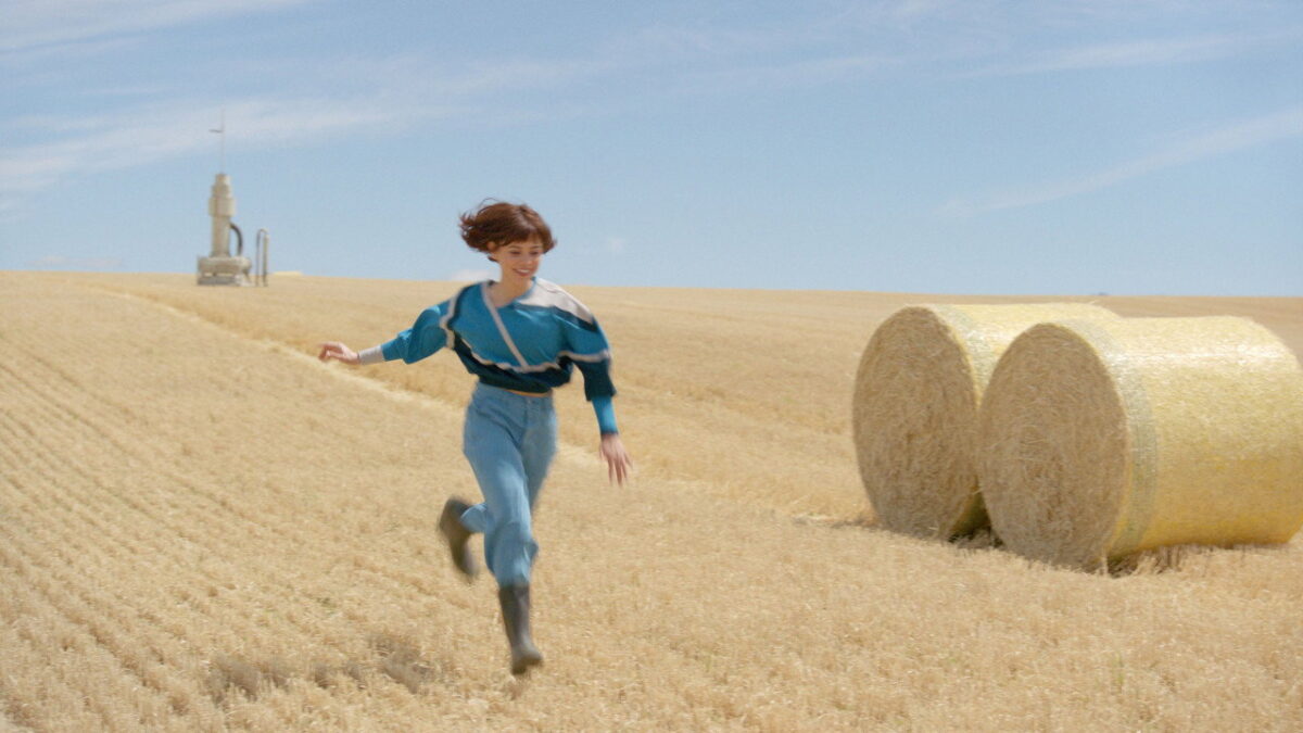 Jenna Ortega as Klara running through a harvested wheat field in Klara and the Sun, directed by Taika Waititi