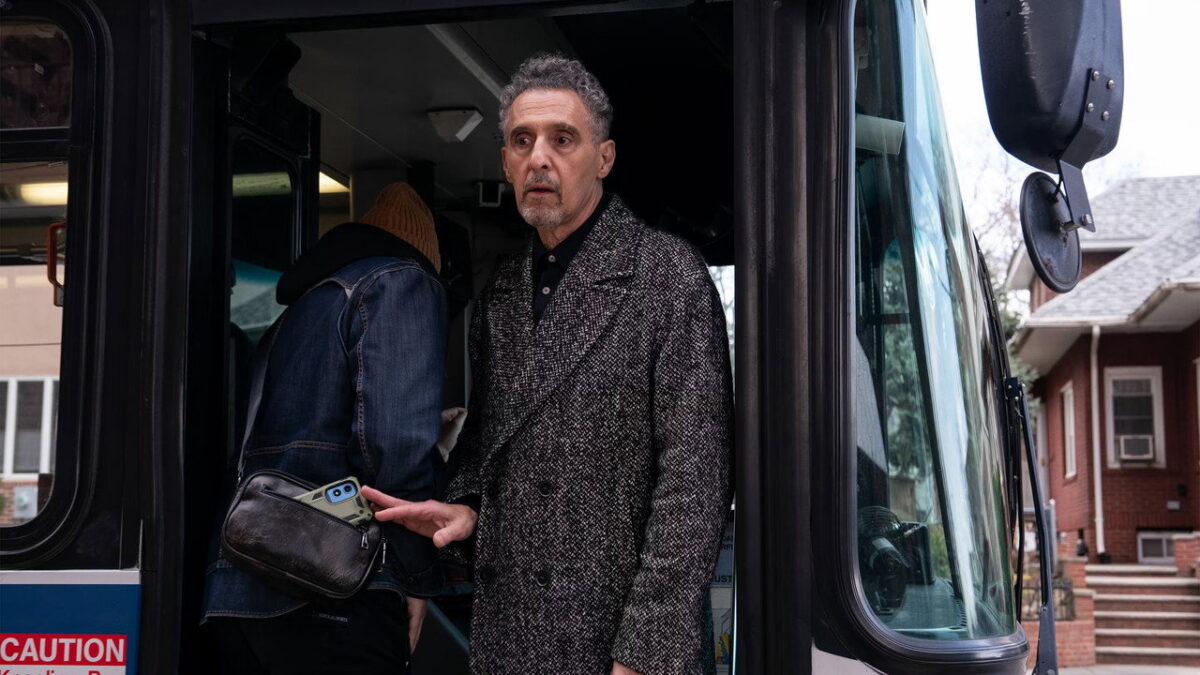 John Turturro as the pickpocket Harry Lehman lifting a phone at a bus door in The Only Living Pickpocket in New York (2026)