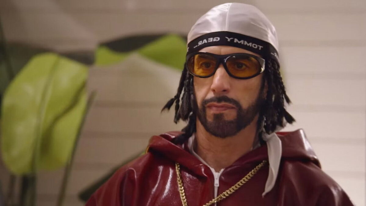 Sacha Baron Cohen as Ali G in a burgundy tracksuit and tinted glasses in Ali G Who Iz I (2026)