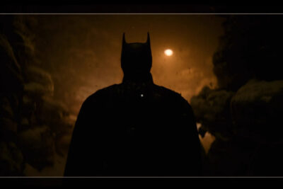 Robert Pattinson's Batman in silhouette against a low orange light in a still from Matt Reeves' Batman films