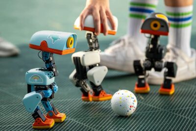 Microduck robots by Pollen Robotics playing football on an outdoor pitch — Image: Pollen Robotics