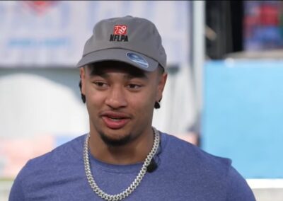 Jaxon Smith-Njigba in a grey NFLPA cap and blue T-shirt, speaking during a TV interview at the 2023 NFL Draft in Kansas City