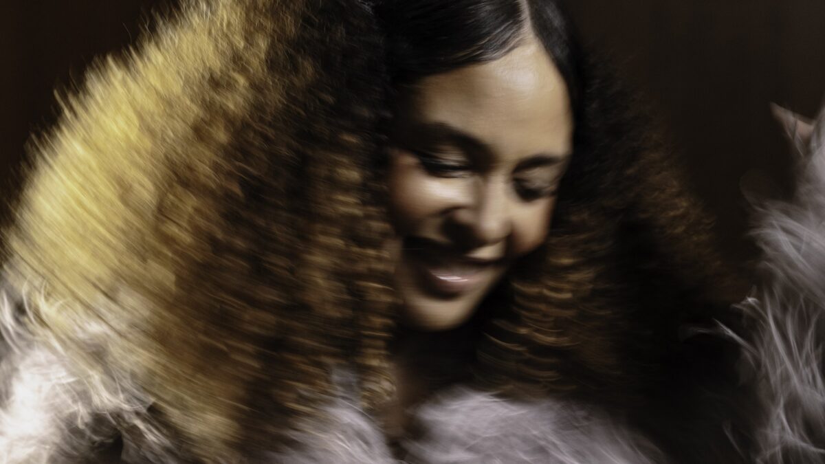 Joy Denalane laughing mid-movement in a motion-blurred press portrait