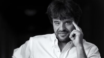 Black-and-white portrait of neuroscientist Karl Deisseroth in a white shirt, his hand resting against his temple