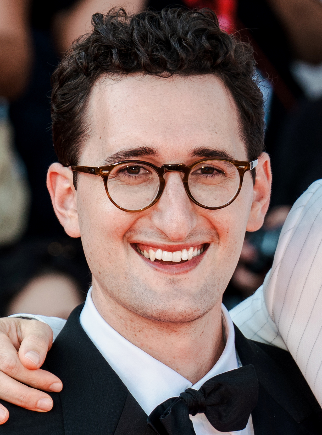Lance Oppenheim smiling in round tortoiseshell glasses and a bow tie at the Primetime premiere, Venice Film Festival 2026