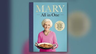 Mary Berry holding a one-pan dish on the cover of her cookbook Mary All in One