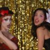 Chappell Roan and Olivia Rodrigo singing in front of a gold tinsel curtain in the expectations music video
