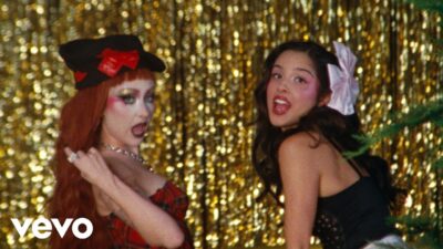 Chappell Roan and Olivia Rodrigo singing in front of a gold tinsel curtain in the expectations music video