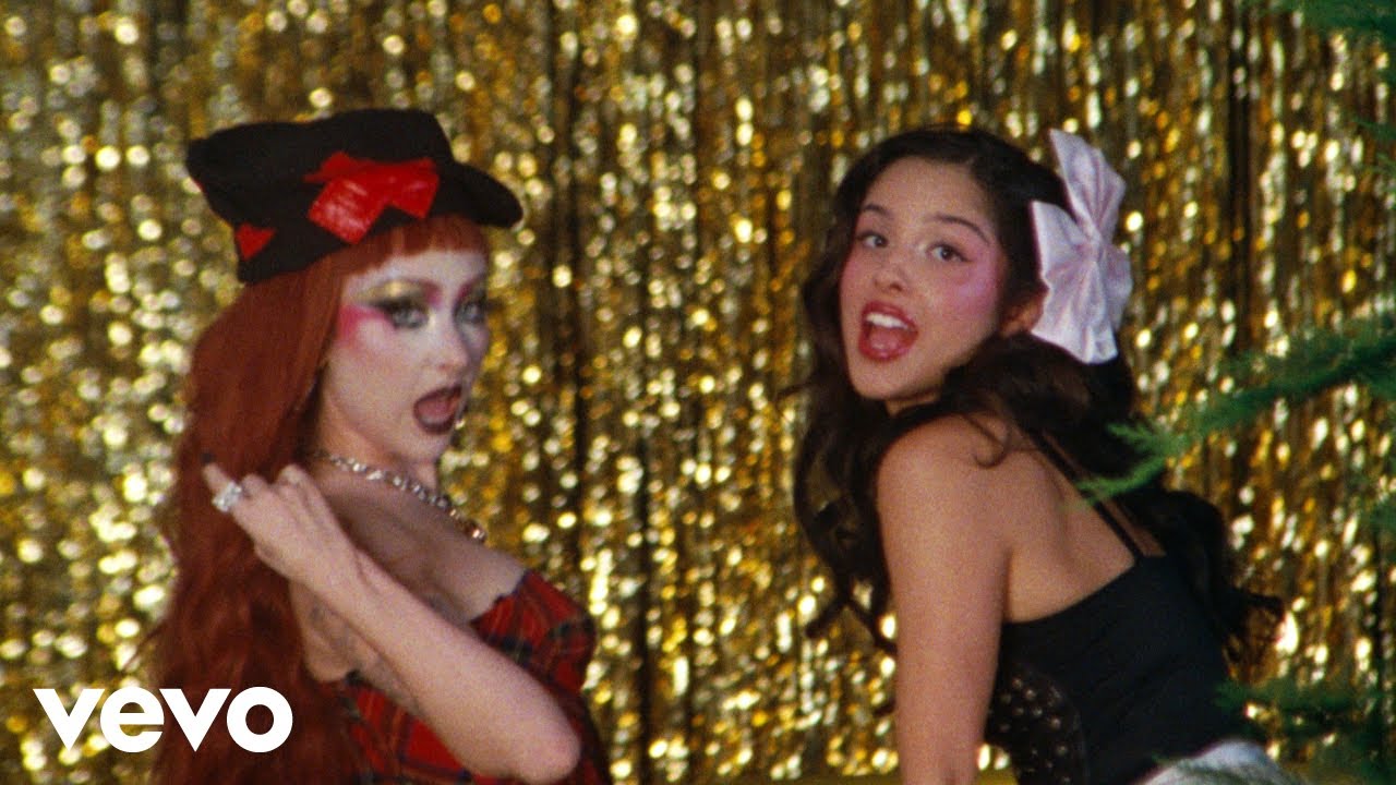 Chappell Roan and Olivia Rodrigo singing in front of a gold tinsel curtain in the expectations music video