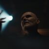 Billy Corgan of The Smashing Pumpkins singing under a spotlight in the Black Stars music video