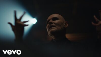 Billy Corgan of The Smashing Pumpkins singing under a spotlight in the Black Stars music video