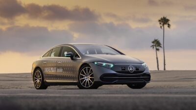 Mercedes-Benz EQS with Drive Pilot and turquoise automated-driving marker lights lit in its headlamps and mirror