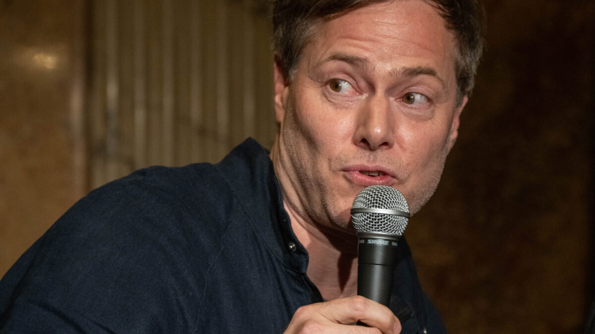Theatre director Milo Rau speaking into a microphone in Vienna