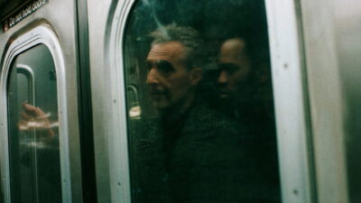 John Turturro as the pickpocket Harry Lehman, seen through a New York subway car window in Noah Segan's The Only Living Pickpocket in New York