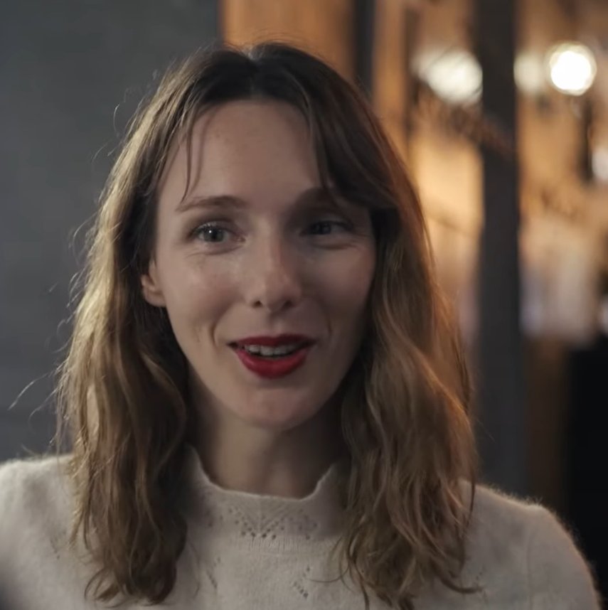 Pauline Clément smiling in a cream knit sweater, still from the short film Mainstream, 2021