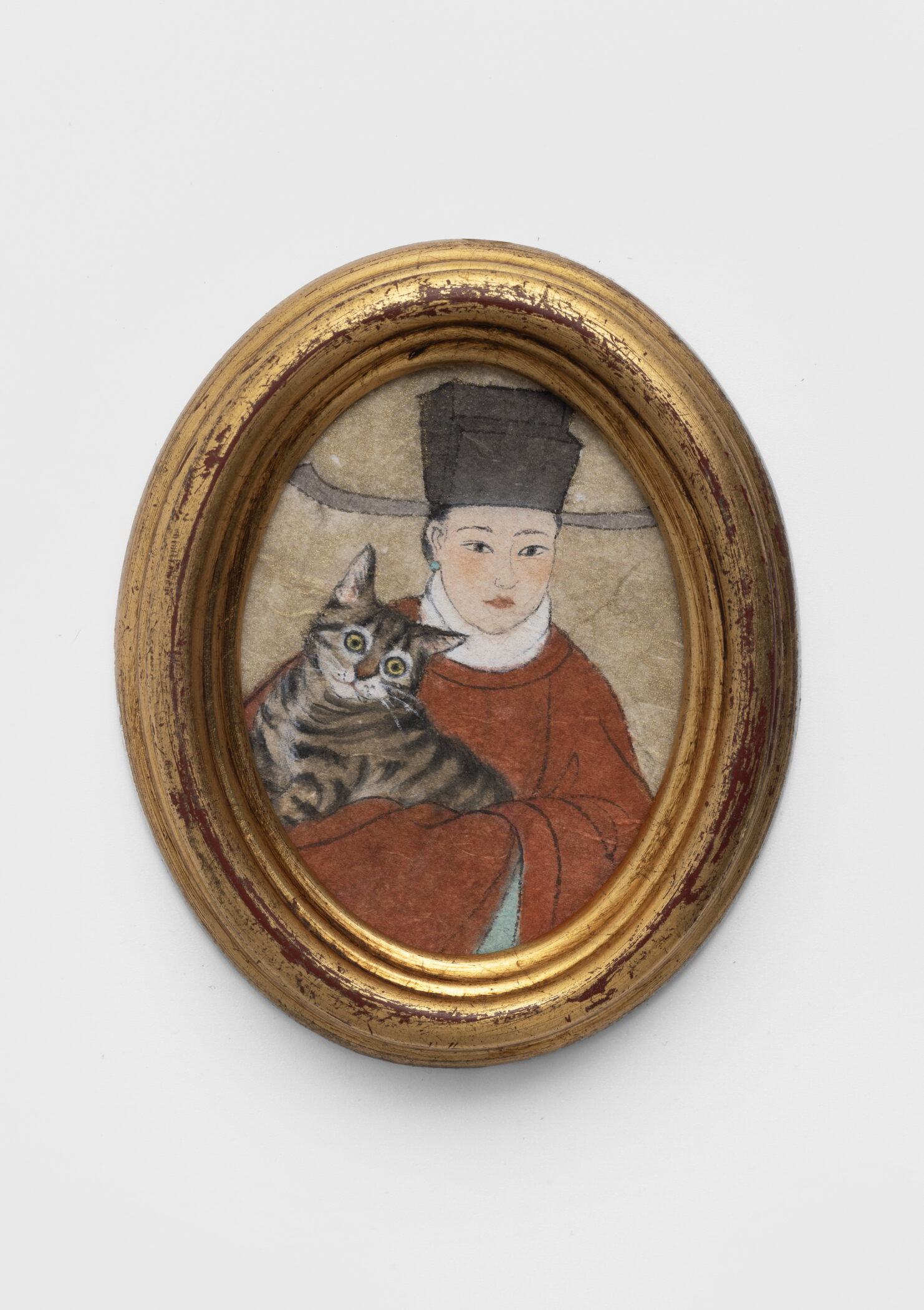 Peng Wei miniature painting of a woman in a red robe and black hat holding a tabby cat, in an oval gilt frame