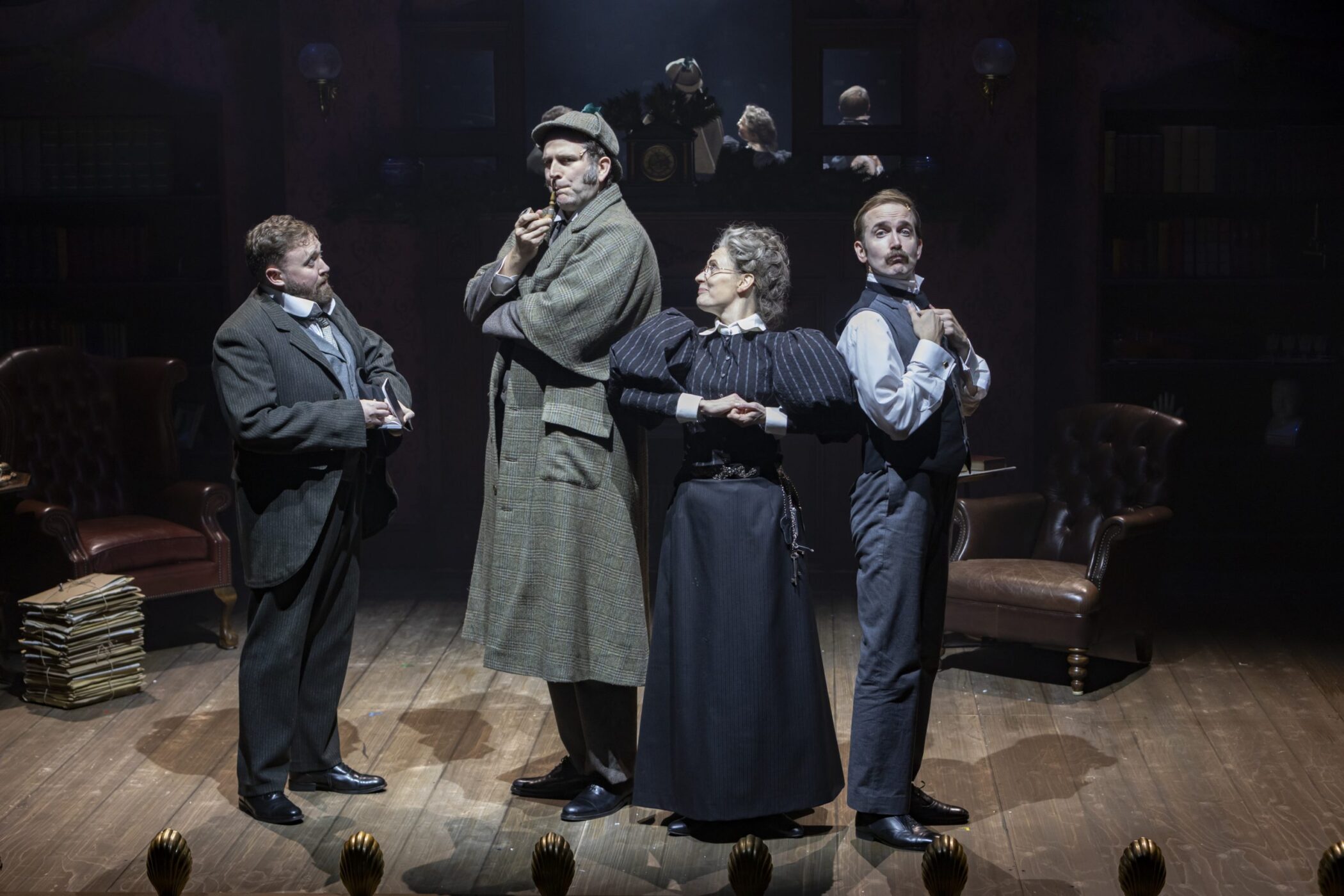 Sherlock Holmes in deerstalker with pipe beside Mrs Hudson and two companions in the Baker Street set of the Birmingham Rep production