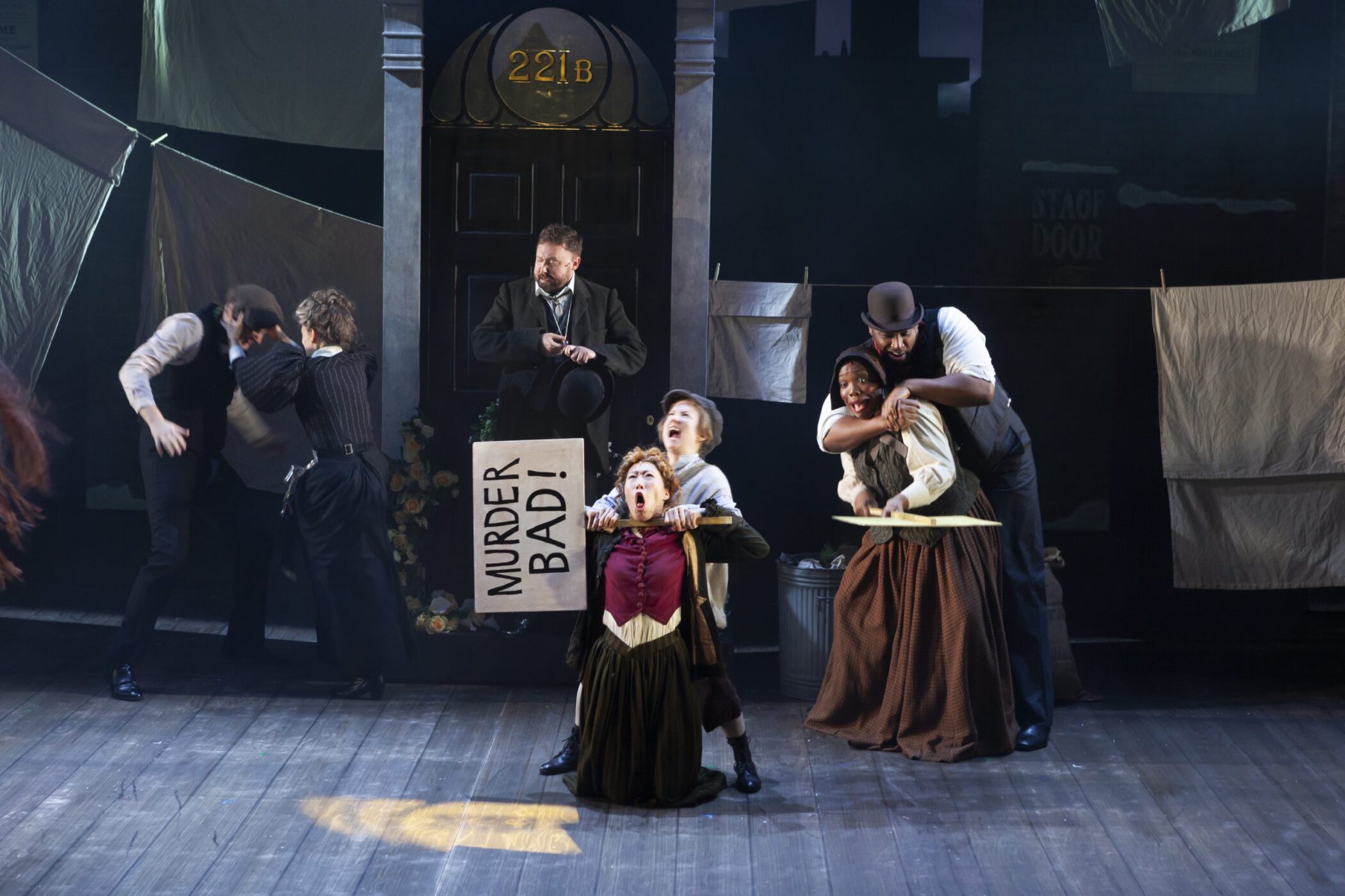 A comic street scene with a Murder Bad placard outside 221b in the Birmingham Rep production