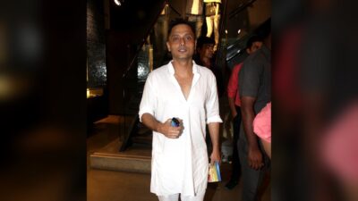 Sujoy Ghosh in a white kurta, holding a phone and a DVD case, at the Kahaani DVD launch, 2012